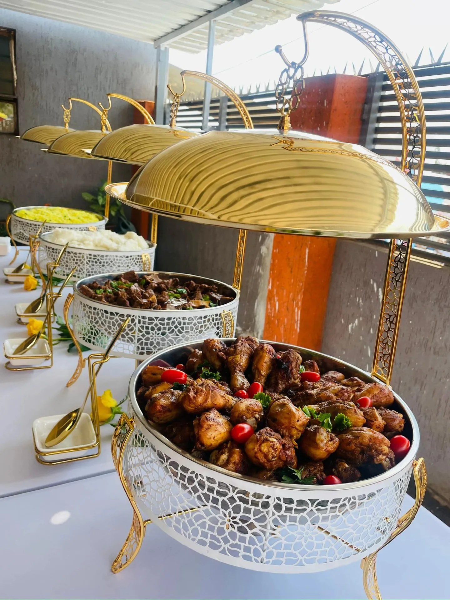 A catered buffet with chicken, beef, rice and mashed potatoes in serving dishes
